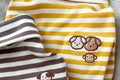 Yellow and white striped fabric with a brown dog embroidery on a gray background